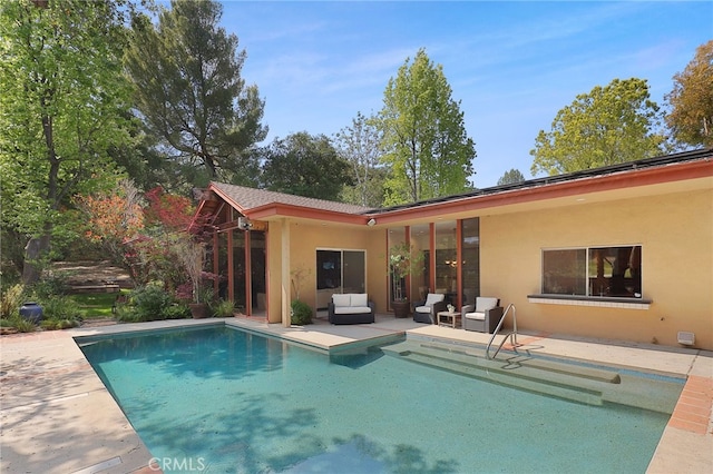 rear view of property featuring outdoor lounge area, an outdoor pool, a patio area, and stucco siding