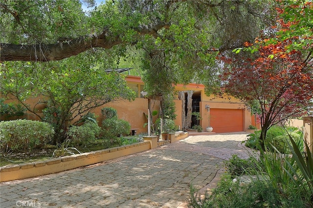 adobe home with decorative driveway and stucco siding