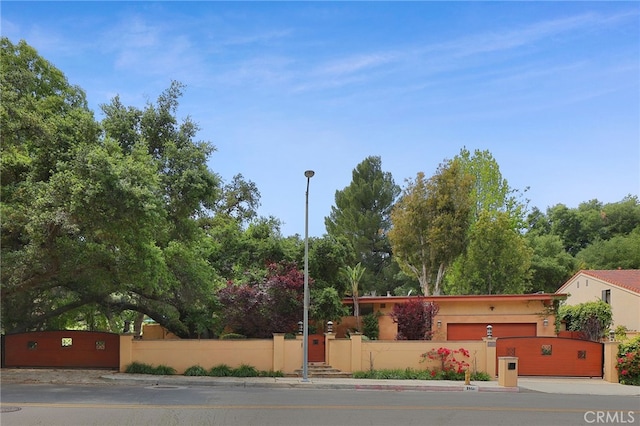 exterior space featuring a fenced front yard, an attached garage, driveway, and stucco siding