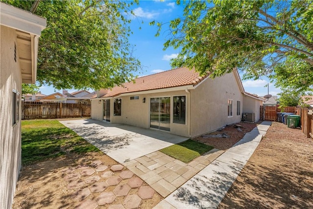 rear view of property with a tile roof, stucco siding, a fenced backyard, a patio area, and central air condition unit
