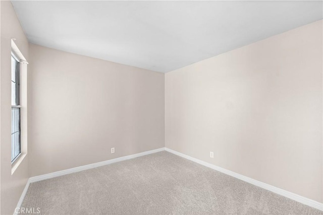 spare room featuring baseboards and carpet flooring