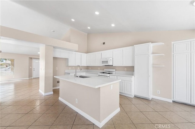 kitchen with light tile patterned floors, light countertops, white appliances, and white cabinetry
