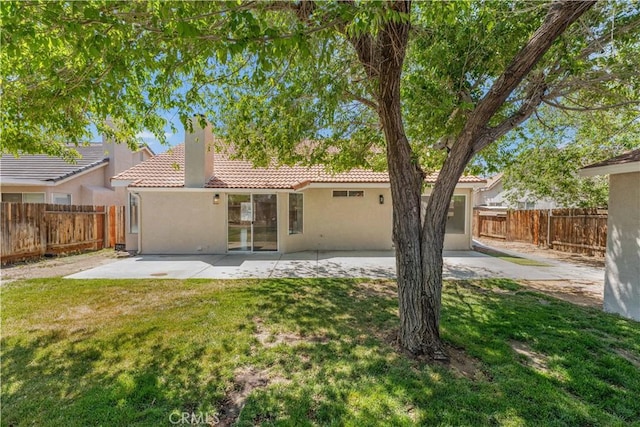 rear view of house with a patio, a fenced backyard, stucco siding, a tiled roof, and a lawn
