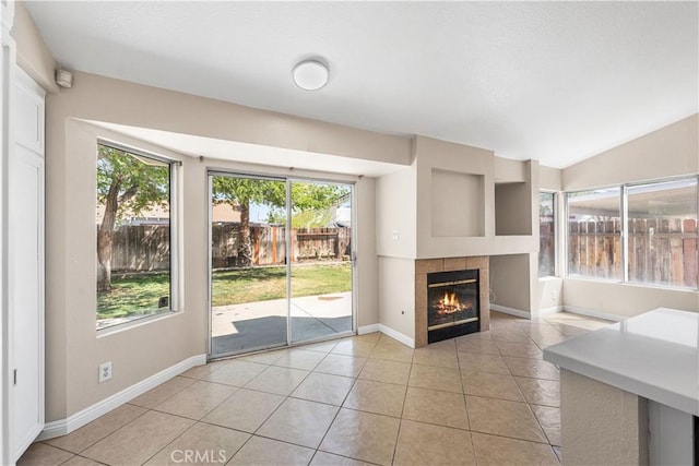 unfurnished living room featuring light tile patterned floors, a healthy amount of sunlight, and a fireplace