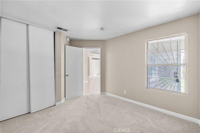 unfurnished bedroom with carpet floors, baseboards, a closet, and visible vents