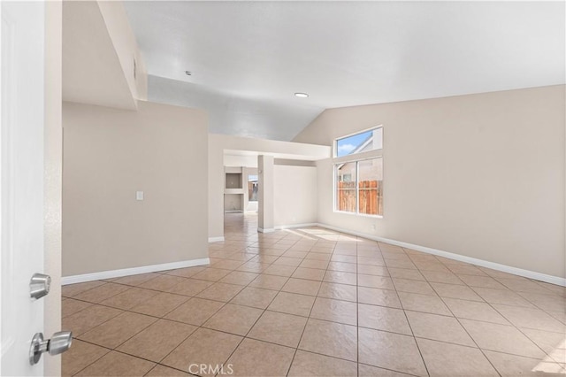 unfurnished room with baseboards, light tile patterned flooring, and lofted ceiling