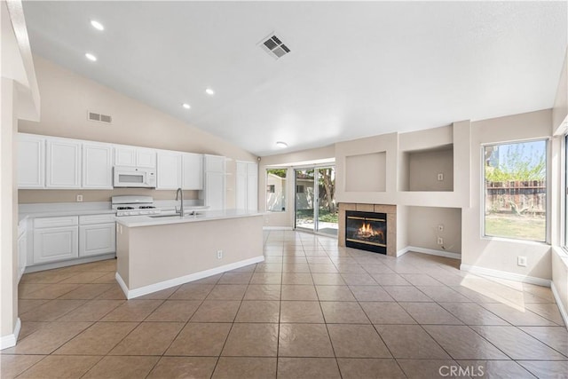 kitchen featuring visible vents, a sink, white microwave, and light tile patterned flooring