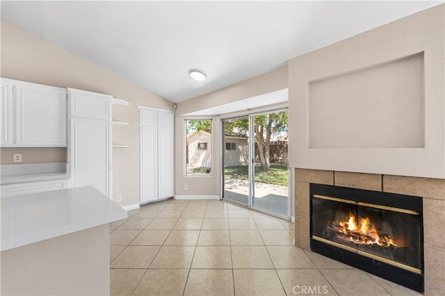 interior space with light tile patterned flooring, baseboards, vaulted ceiling, and a fireplace