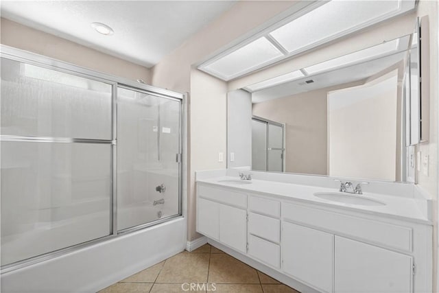 bathroom with a sink, bath / shower combo with glass door, tile patterned floors, and visible vents
