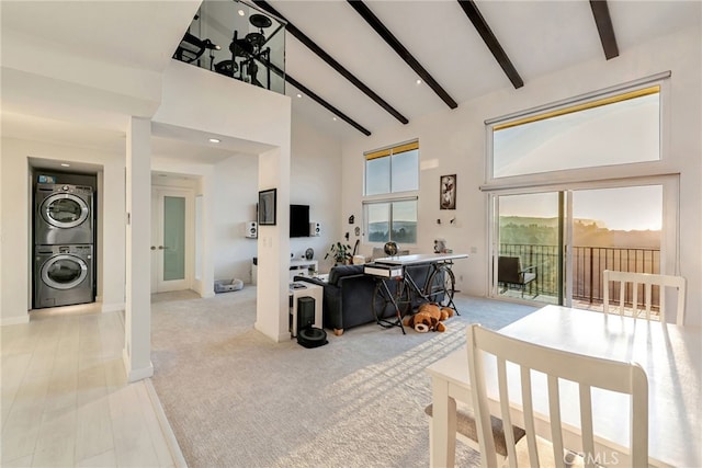 dining room featuring high vaulted ceiling, beam ceiling, stacked washer / dryer, and light colored carpet