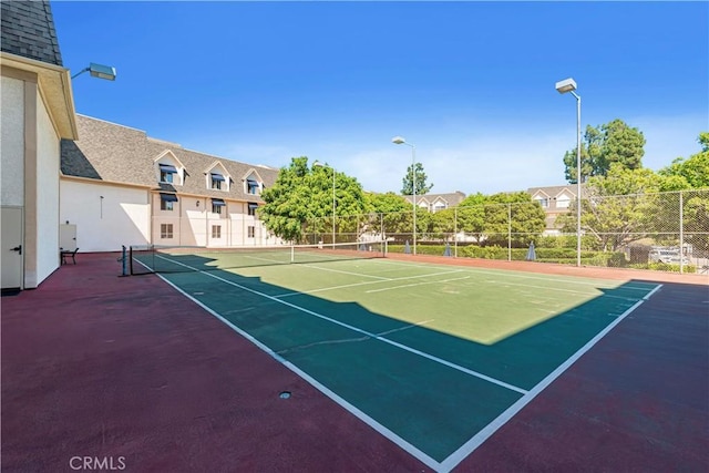 view of tennis court with community basketball court and fence