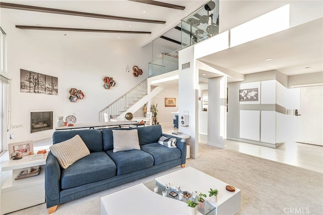 living room featuring visible vents, a towering ceiling, beamed ceiling, stairway, and carpet