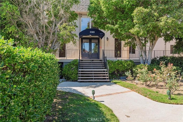 property entrance featuring stucco siding and french doors