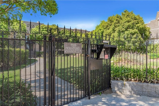 view of gate with fence and a lawn