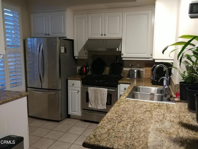 kitchen featuring light tile patterned flooring, under cabinet range hood, white cabinets, a sink, and appliances with stainless steel finishes