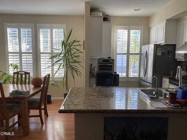 kitchen with a sink, light wood-style flooring, white cabinetry, and a wealth of natural light