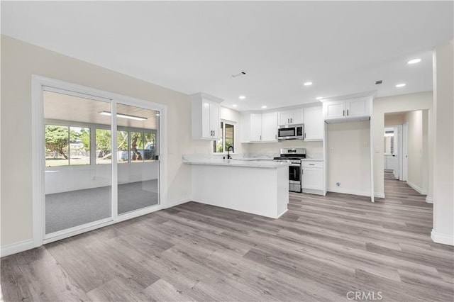 kitchen with stainless steel appliances, baseboards, and light wood-type flooring