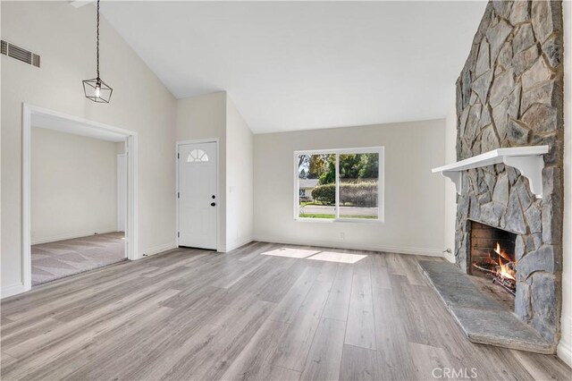 unfurnished living room with visible vents, wood finished floors, a fireplace, baseboards, and high vaulted ceiling