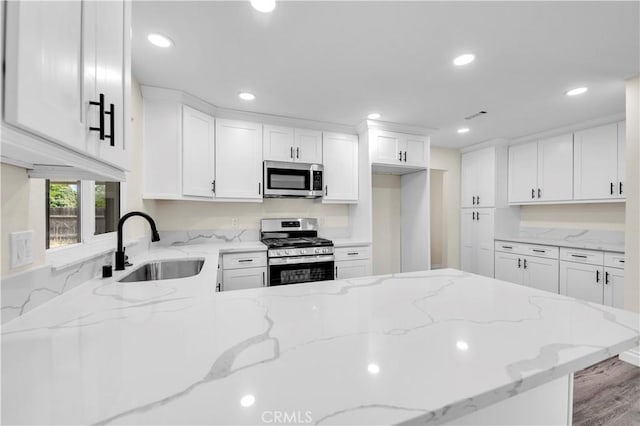 kitchen with a sink, appliances with stainless steel finishes, recessed lighting, and white cabinetry