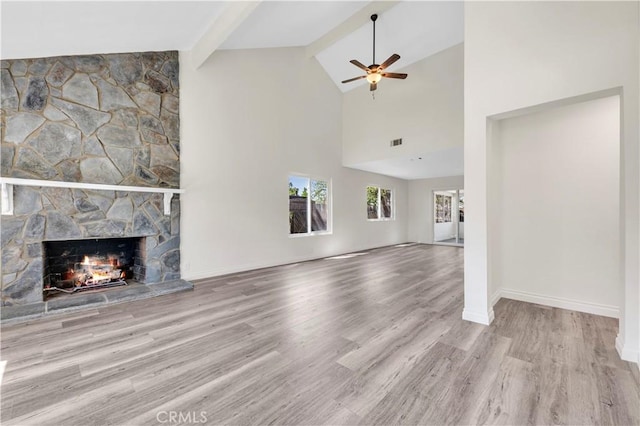 unfurnished living room with a ceiling fan, visible vents, a fireplace, wood finished floors, and beamed ceiling