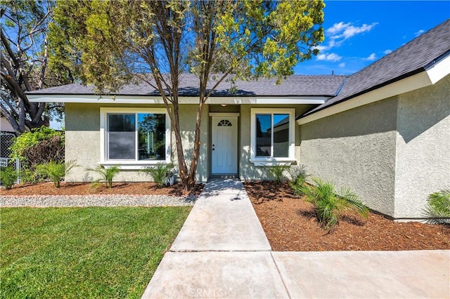entrance to property with a yard and stucco siding