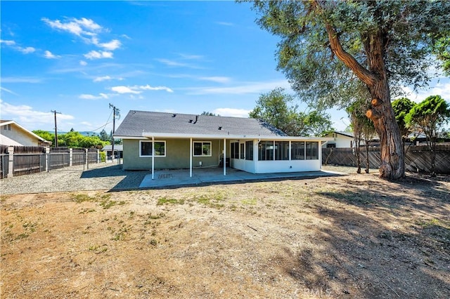 back of house featuring a patio, a fenced backyard, a sunroom, and stucco siding