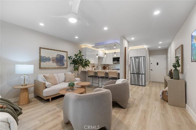 living room featuring light wood-type flooring, recessed lighting, baseboards, and a ceiling fan