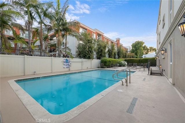 community pool with fence and a patio area
