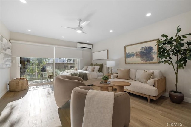 living room with a ceiling fan, a wall mounted air conditioner, baseboards, recessed lighting, and light wood-style flooring