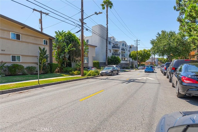 view of road featuring curbs, street lights, sidewalks, and a residential view