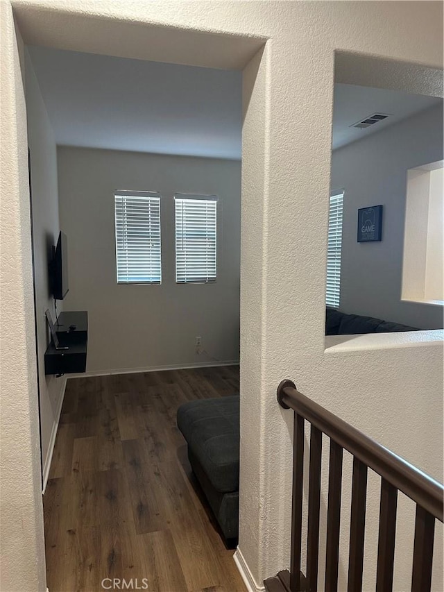 hall with a textured wall, visible vents, and wood finished floors
