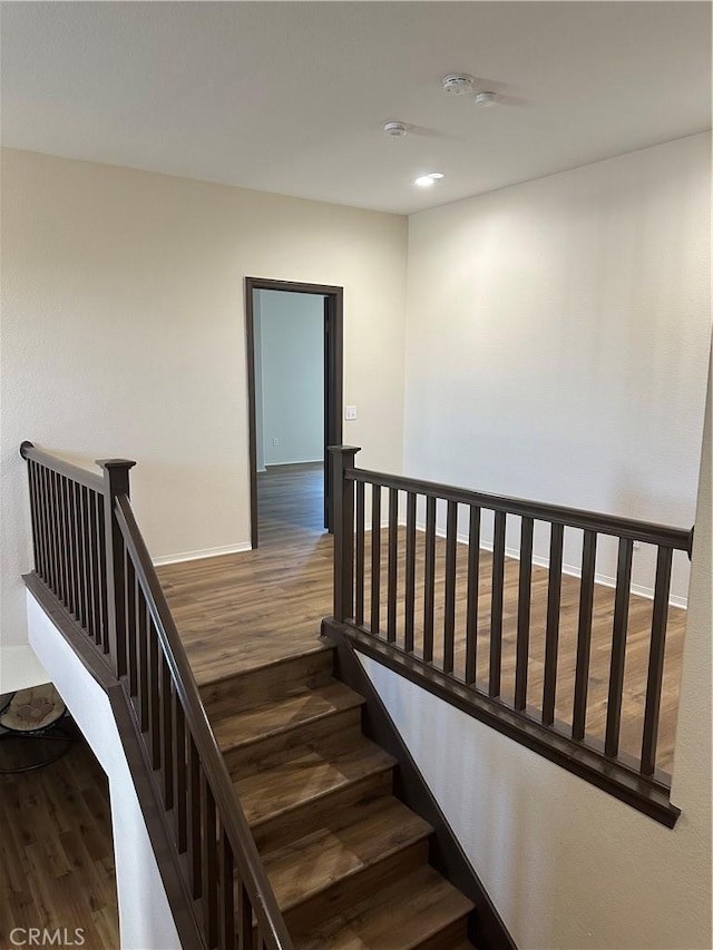 staircase with recessed lighting, baseboards, and wood finished floors