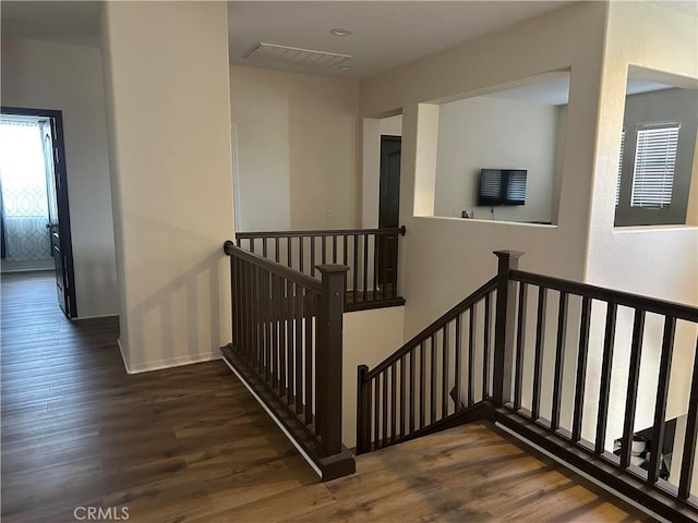 staircase featuring baseboards, wood finished floors, and visible vents