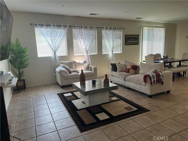 tiled living area featuring plenty of natural light, baseboards, and visible vents