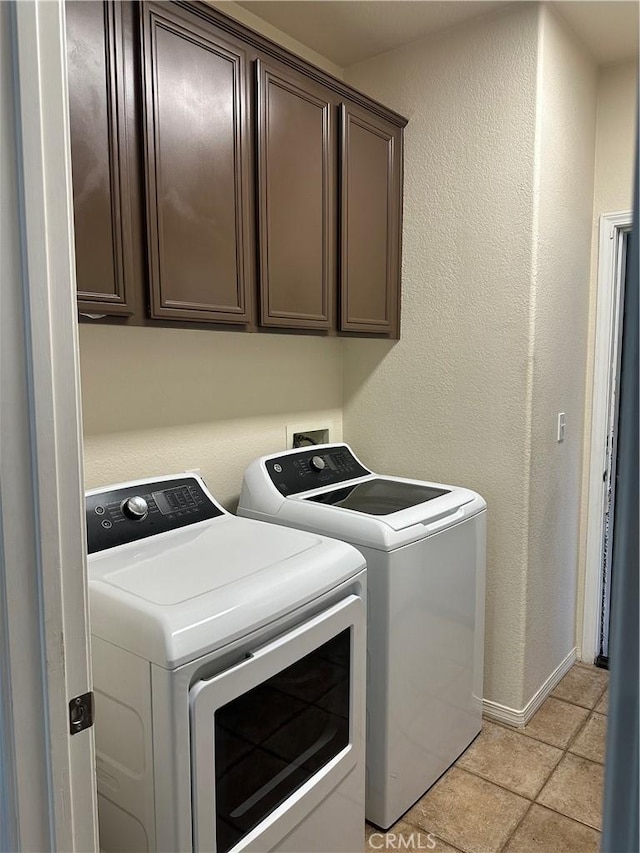laundry area featuring separate washer and dryer, cabinet space, a textured wall, and baseboards