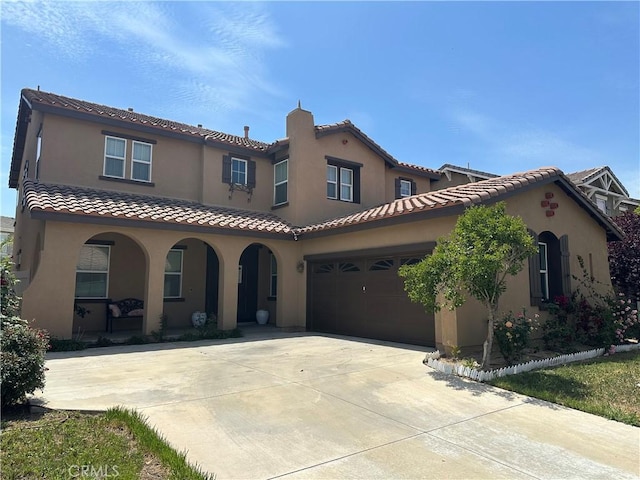 mediterranean / spanish house with covered porch, a tiled roof, driveway, and stucco siding