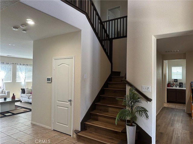 stairway featuring visible vents, recessed lighting, baseboards, and tile patterned floors