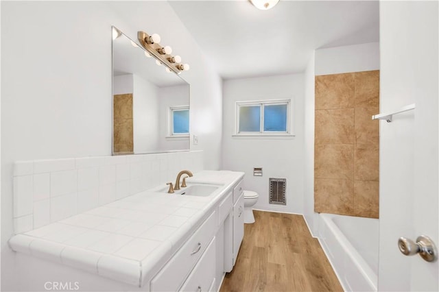 bathroom featuring visible vents, tasteful backsplash, wood finished floors, vanity, and toilet