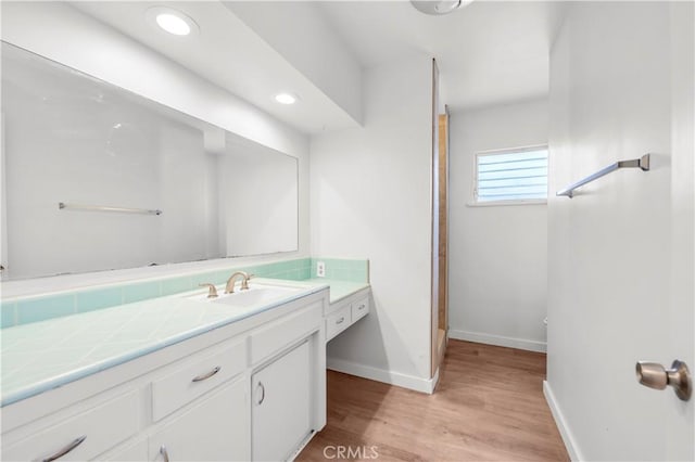 bathroom featuring baseboards, recessed lighting, wood finished floors, and vanity
