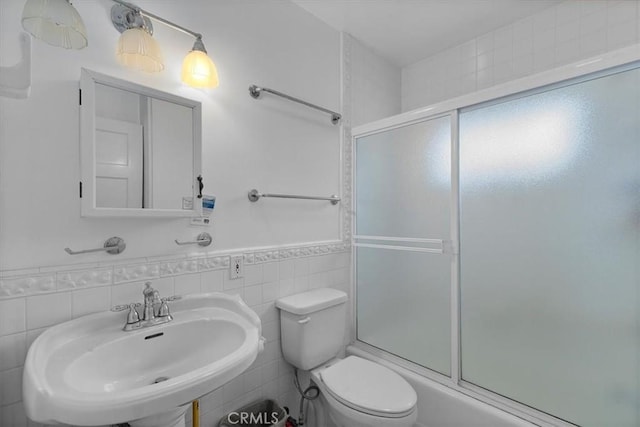 117 Maiden Ln, Avalon, CA 90704 - full bathroom featuring tile walls, a sink, a wainscoted wall, toilet, and shower / bath combination with glass door