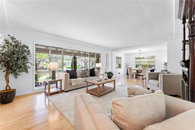 living area featuring baseboards, light wood finished floors, and a notable chandelier