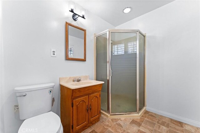bathroom with vanity, baseboards, a stall shower, and toilet