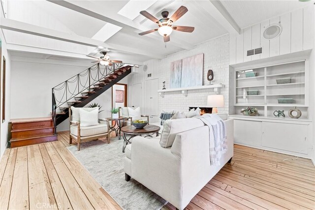 living room with beam ceiling, hardwood / wood-style floors, stairs, a ceiling fan, and visible vents