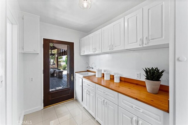 bar featuring baseboards, a sink, and light tile patterned flooring