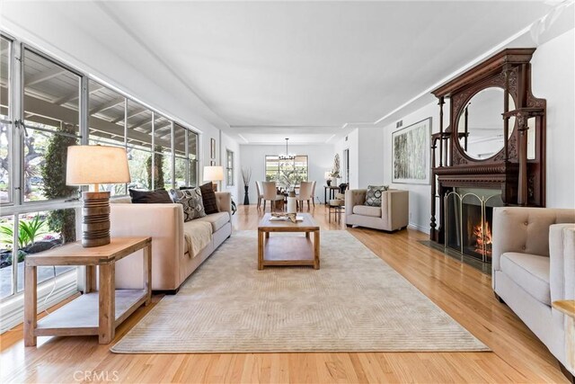 living room with an inviting chandelier, wood finished floors, and a large fireplace