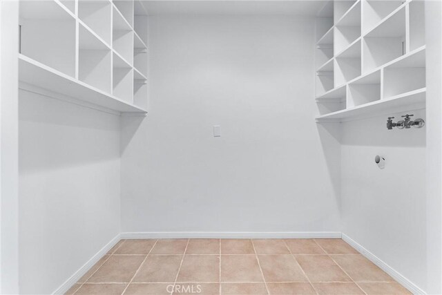 washroom with laundry area, baseboards, and tile patterned flooring