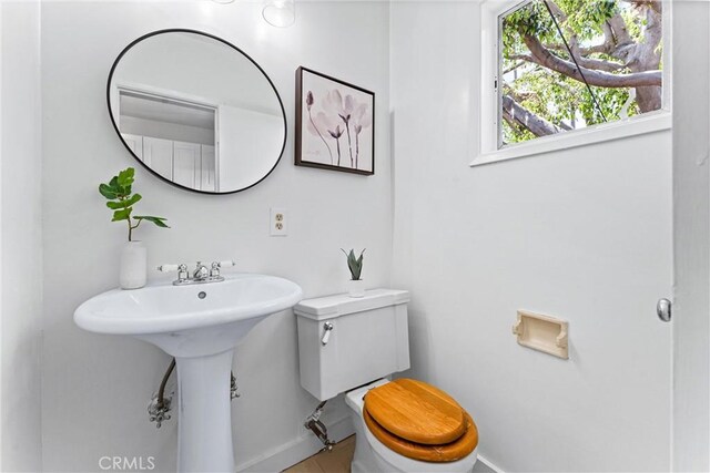 half bath with tile patterned floors, baseboards, and toilet