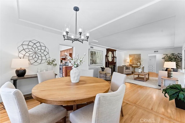 dining area with visible vents, wood finished floors, and a chandelier