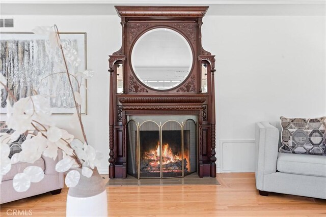room details featuring baseboards, a fireplace with flush hearth, and wood finished floors