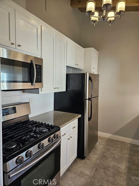 3315 Strongs Dr, Venice, CA 90292 - kitchen featuring white cabinets, an inviting chandelier, stainless steel appliances, stone counters, and tasteful backsplash